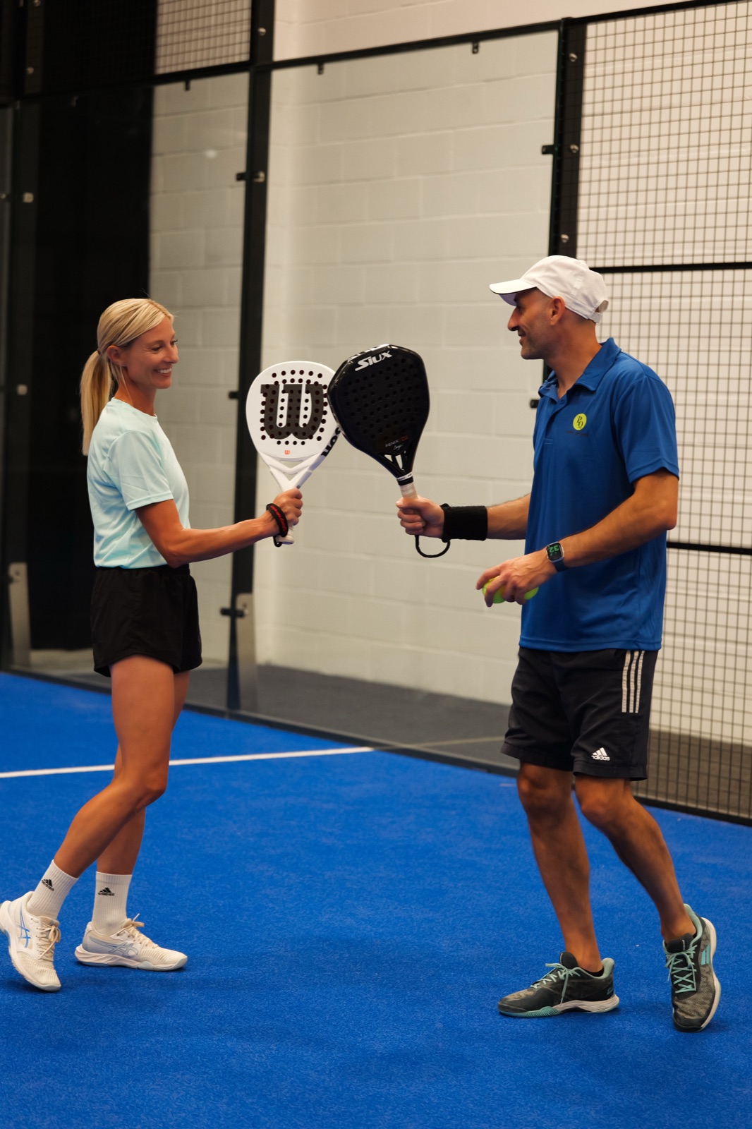 A coach and a player touching racquets on court at Padel Quarter