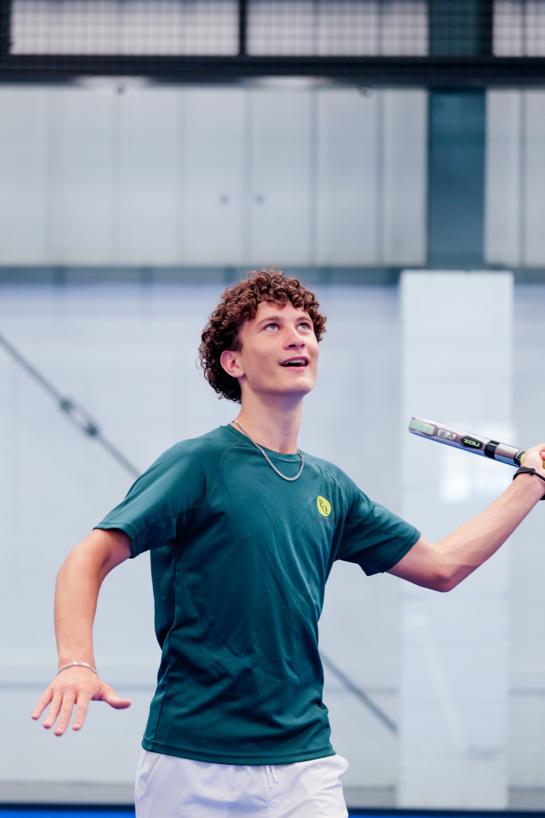 A young player lining up an overhead at Padel Quarter